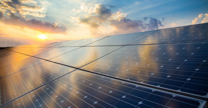 Renewable energy stock image of photovoltaic modules on the background of sunset and cloudy sky.